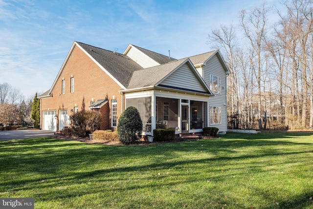 exterior space featuring a front lawn, a garage, and a sunroom