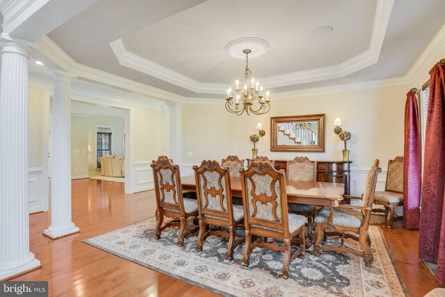 dining room featuring decorative columns, a raised ceiling, and hardwood / wood-style floors