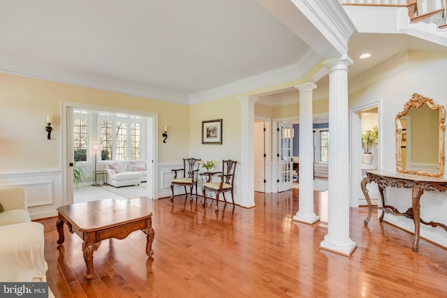 living room featuring decorative columns, plenty of natural light, and light hardwood / wood-style flooring