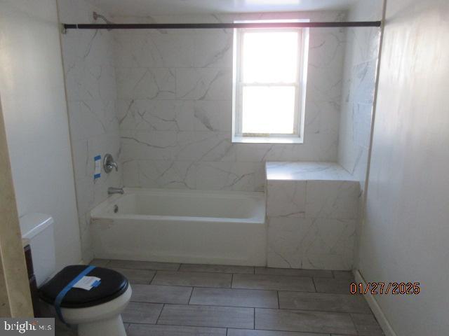 bathroom featuring tiled shower / bath and toilet