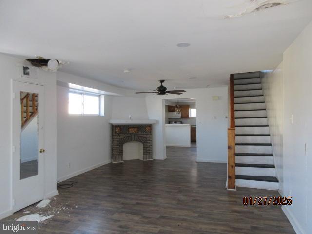 unfurnished living room featuring dark wood-type flooring and ceiling fan