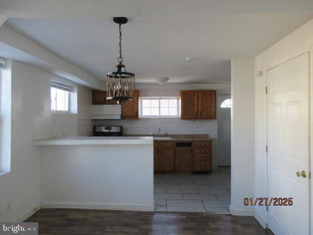 kitchen featuring sink, range, decorative light fixtures, plenty of natural light, and kitchen peninsula