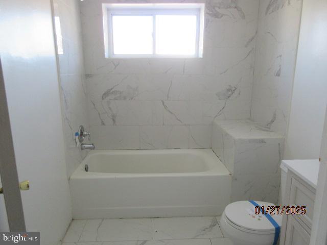 full bathroom featuring tiled shower / bath combo, vanity, and toilet