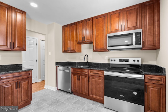 kitchen featuring stainless steel appliances, sink, and dark stone countertops