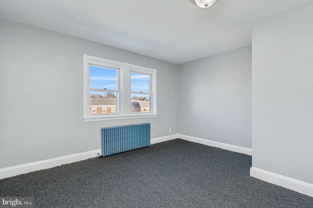 empty room featuring dark colored carpet and radiator heating unit