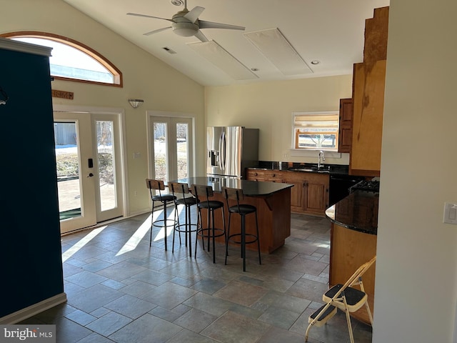 kitchen with a kitchen bar, a wealth of natural light, stainless steel fridge, and a kitchen island