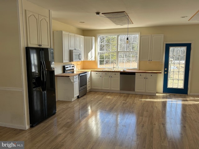 kitchen with sink, stainless steel appliances, light hardwood / wood-style floors, white cabinets, and wood counters