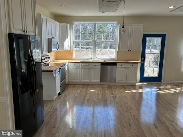 kitchen with white cabinetry, butcher block countertops, decorative light fixtures, and stainless steel appliances