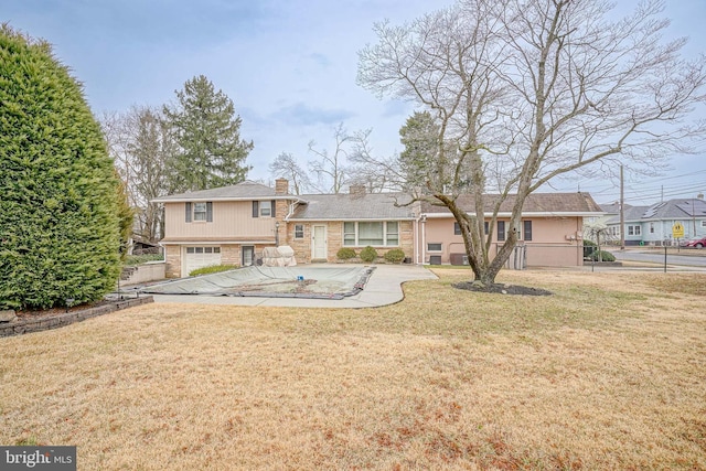 view of front of property featuring a front lawn, a chimney, and an attached garage