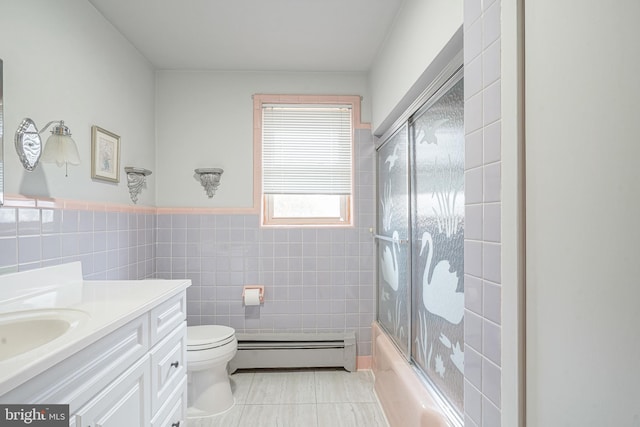 bathroom featuring tile walls, bath / shower combo with glass door, toilet, a baseboard heating unit, and vanity