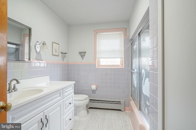 bathroom with toilet, a baseboard heating unit, vanity, tile walls, and wainscoting