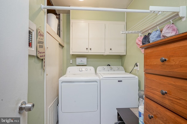 washroom with visible vents, independent washer and dryer, and cabinet space