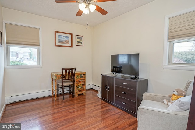 sitting room featuring a baseboard radiator, a textured ceiling, a ceiling fan, and dark wood-style flooring