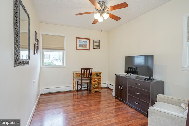 living area featuring ceiling fan, a textured ceiling, baseboards, and wood finished floors