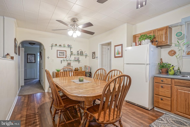 dining room with arched walkways, dark wood finished floors, and crown molding