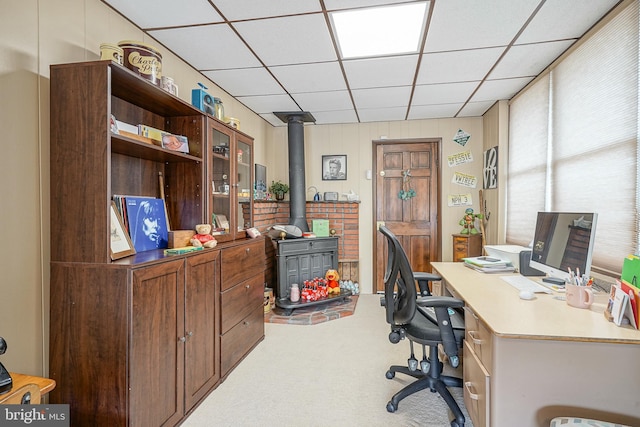 office area featuring carpet floors, a paneled ceiling, and a wood stove