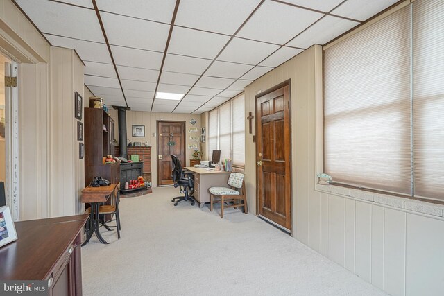 carpeted office with a wood stove and a paneled ceiling