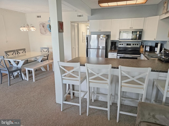 kitchen with a kitchen bar, kitchen peninsula, white cabinets, and appliances with stainless steel finishes