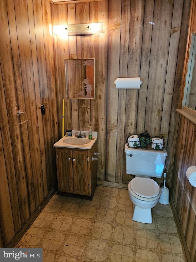 bathroom with vanity, toilet, and wood walls