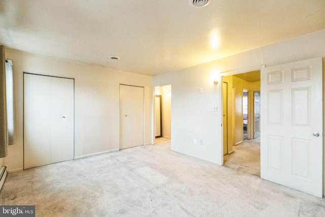 unfurnished bedroom with light carpet and two closets