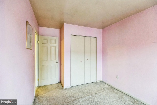 unfurnished bedroom featuring light colored carpet and a closet