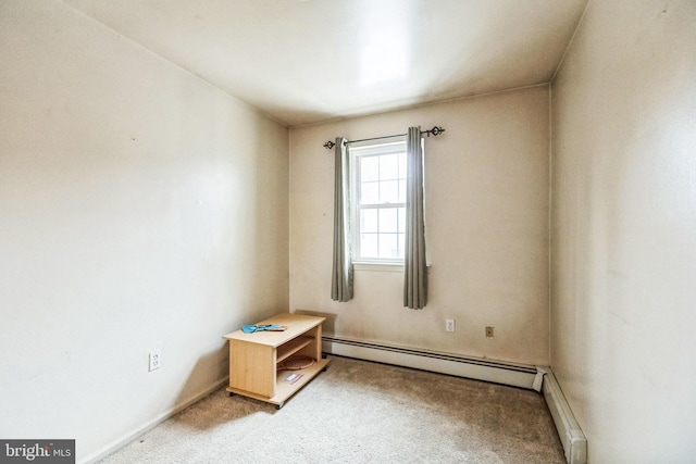 empty room featuring a baseboard heating unit and carpet floors