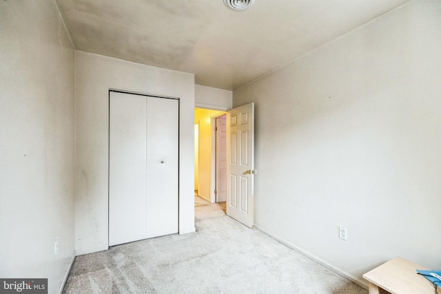 unfurnished bedroom with light carpet and a closet