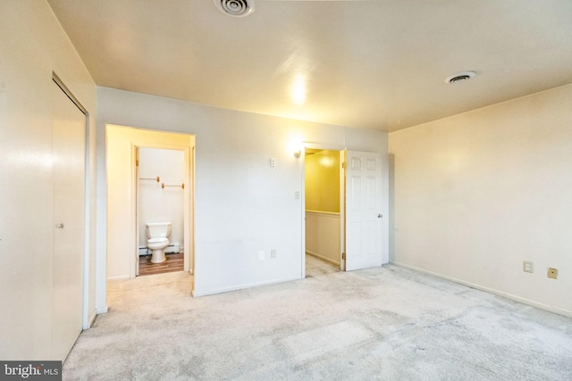 unfurnished bedroom featuring a closet, connected bathroom, and light carpet