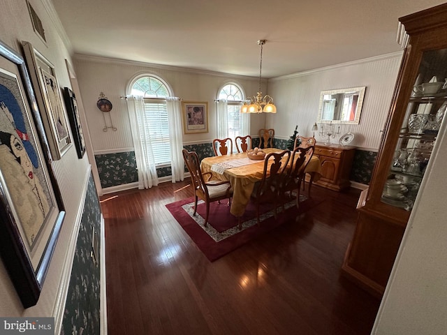 dining area with dark wood-type flooring, ornamental molding, and an inviting chandelier