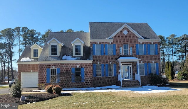 colonial house featuring a garage and a front lawn