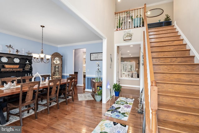 dining room featuring crown molding, a towering ceiling, hardwood / wood-style floors, and a chandelier