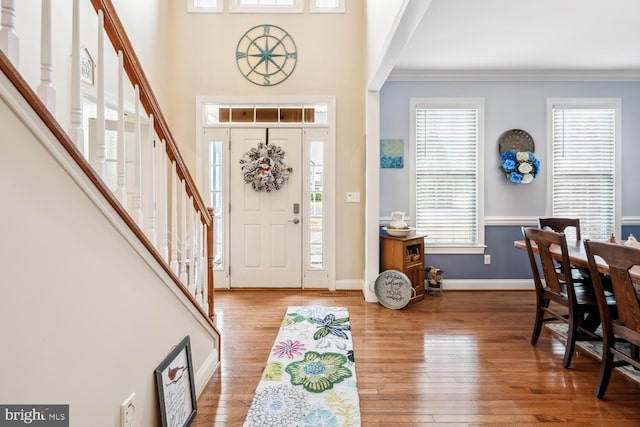 entryway featuring hardwood / wood-style flooring, ornamental molding, and a high ceiling