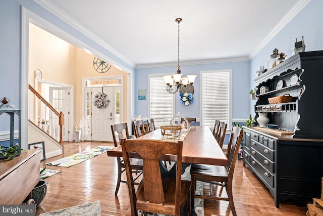 dining area featuring crown molding, an inviting chandelier, and light wood-type flooring