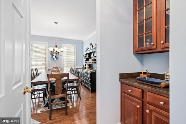 dining area with ornamental molding, a chandelier, and light wood-type flooring