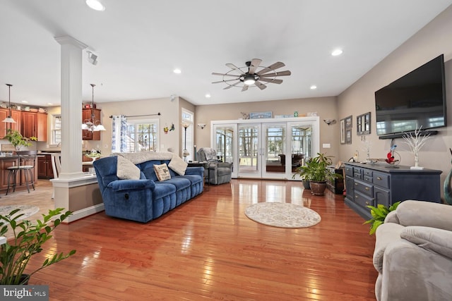 living room with french doors, decorative columns, and light wood-type flooring