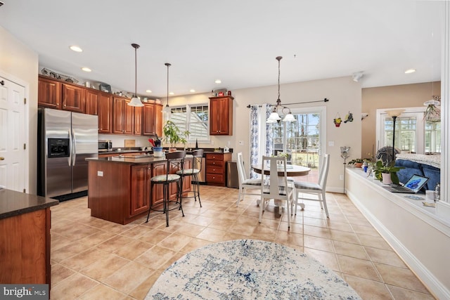 kitchen with pendant lighting, light tile patterned flooring, a center island, and appliances with stainless steel finishes