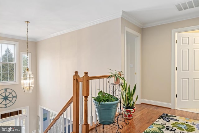 corridor featuring crown molding, a notable chandelier, and light hardwood / wood-style floors