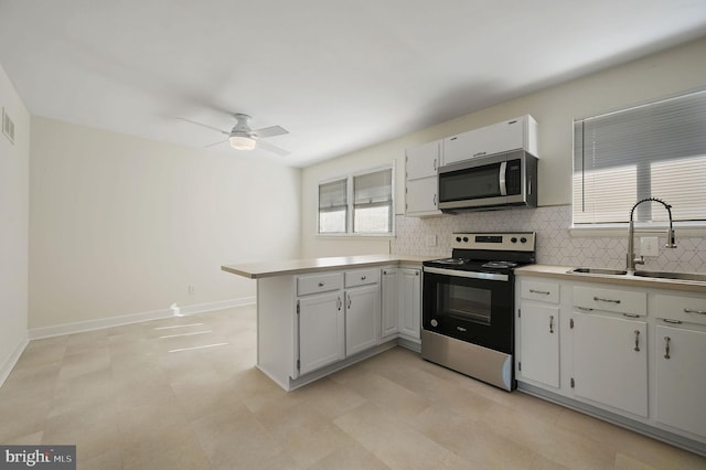 kitchen with appliances with stainless steel finishes, sink, white cabinets, decorative backsplash, and kitchen peninsula