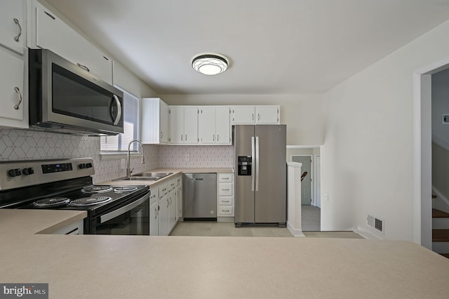 kitchen featuring tasteful backsplash, sink, white cabinets, and appliances with stainless steel finishes