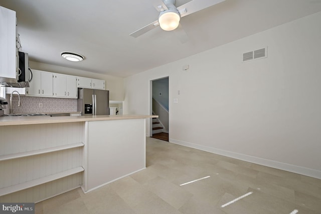 kitchen with sink, white cabinetry, backsplash, stainless steel appliances, and kitchen peninsula