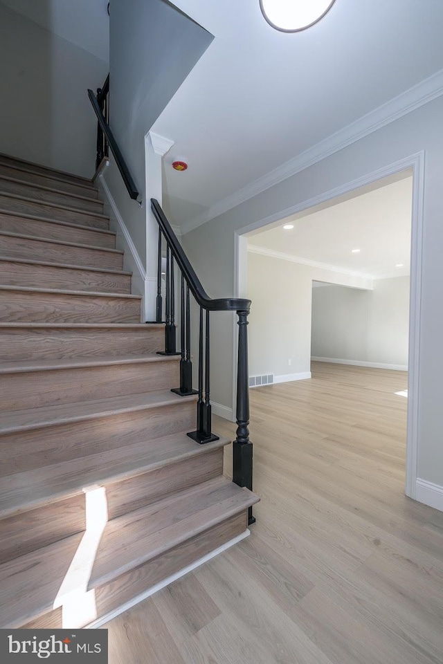 stairway featuring ornamental molding and hardwood / wood-style floors