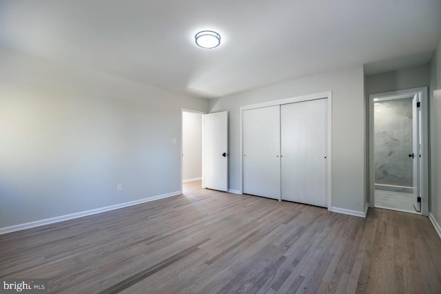 unfurnished bedroom with connected bathroom, light hardwood / wood-style floors, and a closet