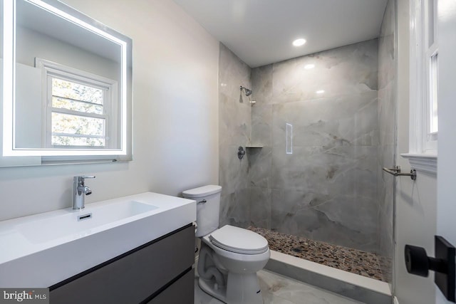 bathroom featuring tiled shower, vanity, and toilet