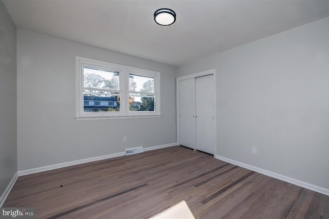 unfurnished bedroom featuring dark wood-type flooring and a closet