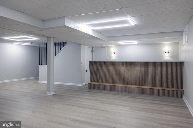 basement featuring a paneled ceiling and light wood-type flooring