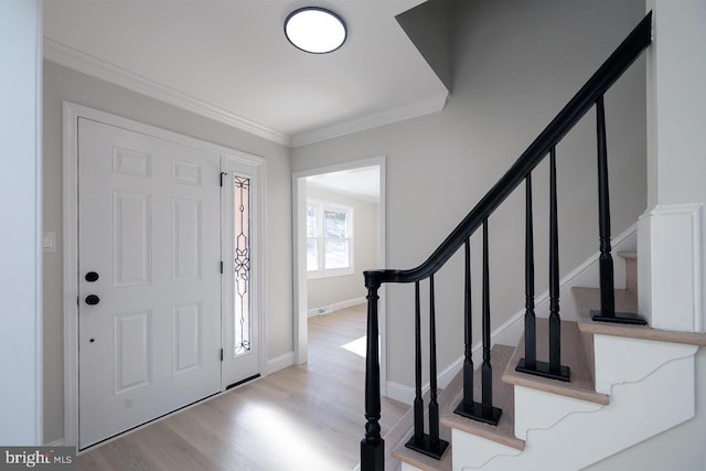 foyer entrance featuring crown molding and light hardwood / wood-style flooring