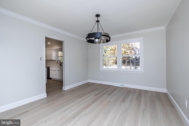 unfurnished dining area with a notable chandelier, light hardwood / wood-style flooring, ornamental molding, and sink