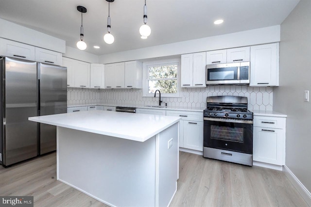 kitchen featuring appliances with stainless steel finishes, a center island, white cabinets, and decorative light fixtures