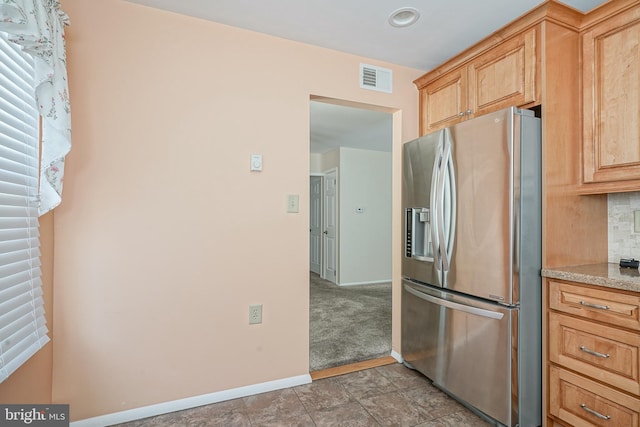 kitchen with stainless steel refrigerator with ice dispenser, light brown cabinetry, and decorative backsplash