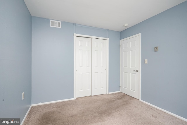 unfurnished bedroom featuring light carpet and a closet